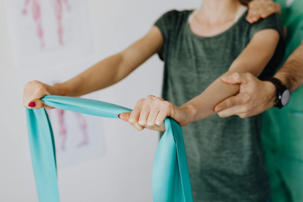 a woman using a PT band with guidance from her PT as she strengthens her arms