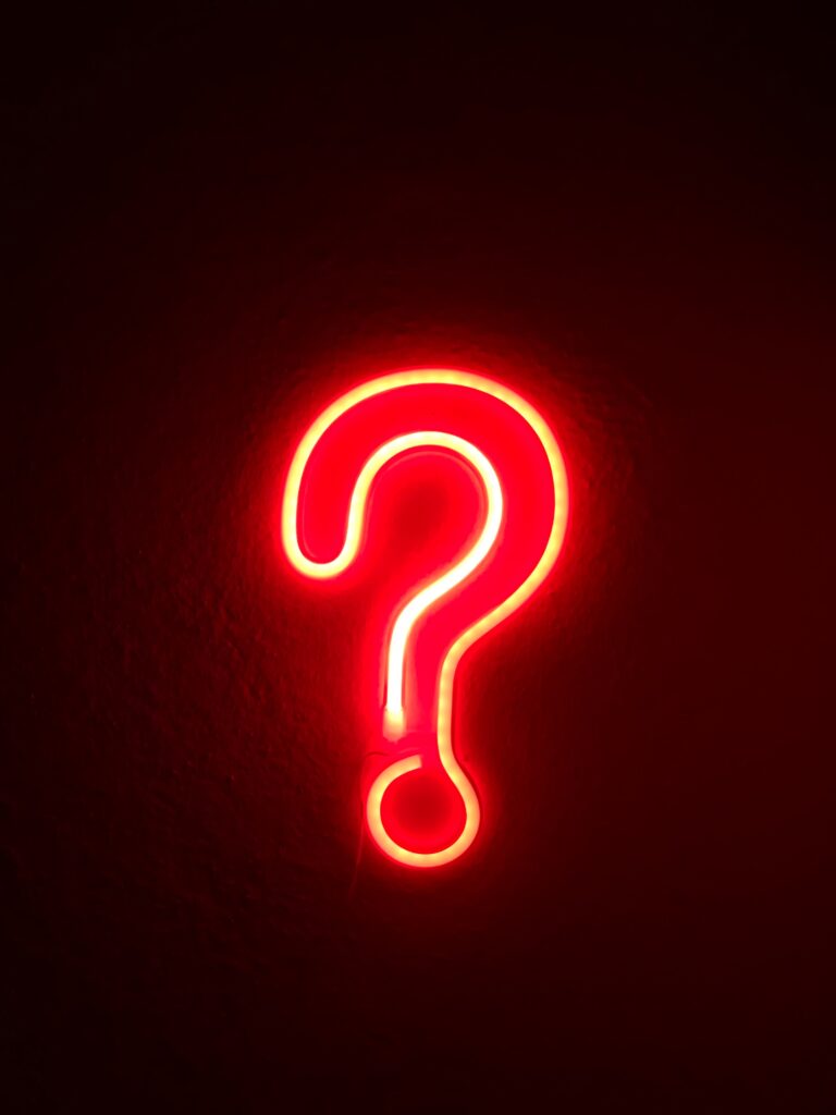 red neon sign of a question mark on a black background
